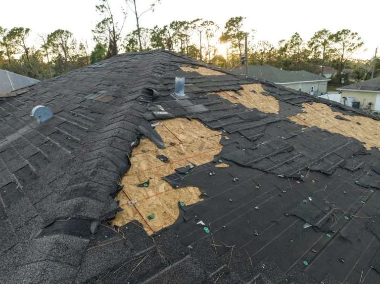 Damaged roof with missing shingles and exposed decking after a storm, highlighting the need for professional roof repair and restoration.